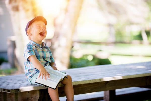 Picture young boy with a book laughing