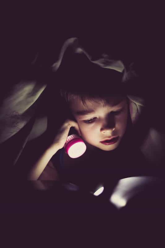 Picture Child Reading Under the Blanket with Flashlight