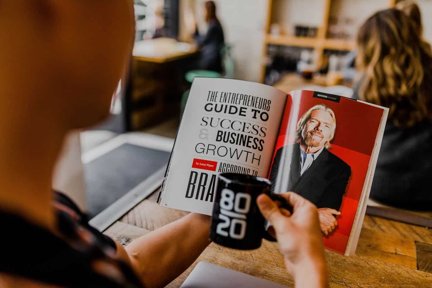 person reading business book with coffee mug